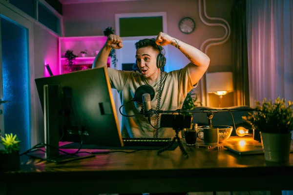 Young man play video games on pc computer while streaming to social media or internet online playtrough or walktrough video male gamer having fun at home wear headphone happy winning copy space