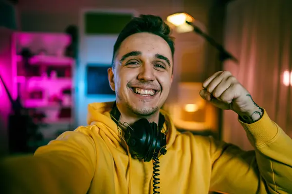 Self portrait of one man caucasian male streamer blogger or content creator with headphones on his head happy smile confident in his studio copy space user generated content UGC