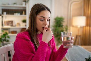 one woman young caucasian female take drugs medicine vitamin at home clipart