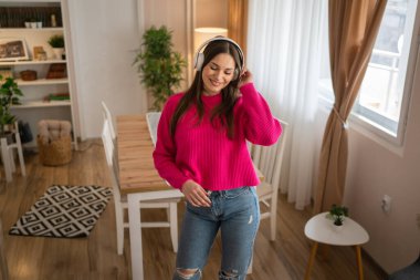 One woman young caucasian female teenager dancing alone at home with headphones on her head having fun while listen to the music happy smile real people copy space