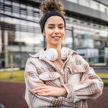 Genç bir yetişkin kadın kulaklıklı, beyaz, modern, mutlu bir kadın. Şehirde gerçek bir insan, güz ya da bahar günlerinde boşluğu doldurur.