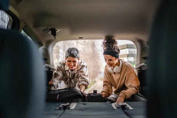 two beautiful women student mother and daughter female travel concept take luggage baggage suitcase and other stuff belongings from back of car while moving into dormitory on college campus or travel