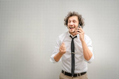 Kafkasyalı bir erkek işadamı, akıllı cep telefonuyla dışarıda dikilirken telefonla konuşur. Beyaz gömlek giyer, kendine güveni tam bir başarı kazanır.