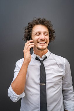 Kafkasyalı bir erkek işadamı, akıllı cep telefonuyla dışarıda dikilirken telefonla konuşur. Beyaz gömlek giyer, kendine güveni tam bir başarı kazanır.