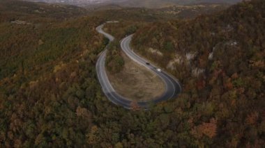 Araç, sonbahar günü dağlık alanda hava manzaralı yolculuk yapar.