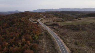 Araç, sonbahar günü dağlık alanda hava manzaralı yolculuk yapar.