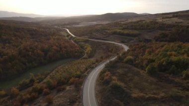 Araç, sonbahar günü dağlık alanda hava manzaralı yolculuk yapar.