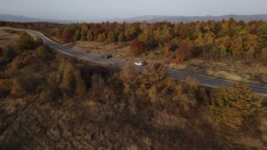 Araç, sonbahar günü dağlık alanda hava manzaralı yolculuk yapar.