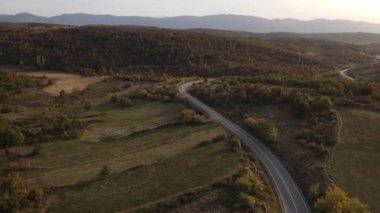 Araç, sonbahar günü dağlık alanda hava manzaralı yolculuk yapar.