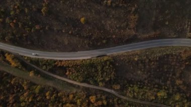 Araç, sonbahar günü dağlık alanda hava manzaralı yolculuk yapar.