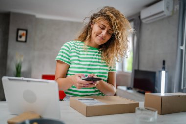 Beyaz bir kadın, online alışveriş ürünlerinin nakliye detaylarını kontrol etmek için akıllı telefon kullanıyor. Akıllı telefon uygulaması başvurusunu kontrol edin. Çevrimiçi detaylar mutlu bir gülümseme.