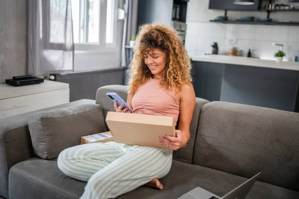 Beyaz bir kadın, online alışveriş ürünlerinin nakliye detaylarını kontrol etmek için akıllı telefon kullanıyor. Akıllı telefon uygulaması başvurusunu kontrol edin. Çevrimiçi detaylar mutlu bir gülümseme.