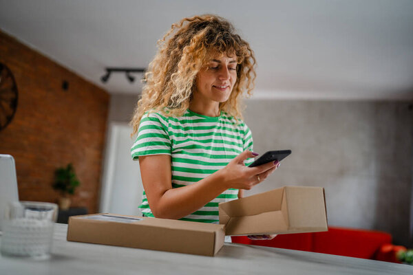 one caucasian woman use smart phone to check shipping details of the received package online shopping product arrived stand with smartphone app application check online details happy smile