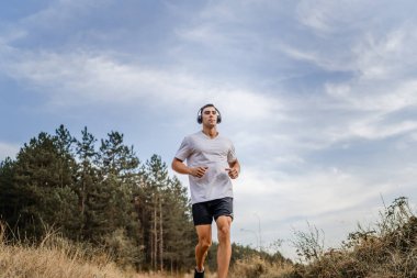 Bir erkek beyaz erkek sporcu doğada toprak yolda koşuyor sonbaharda ya da yazın koşuyor spor yapıyor spor yapıyor sağlıklı yaşam tarzı kavramı gerçek insanlar mekanı kopyalıyor.