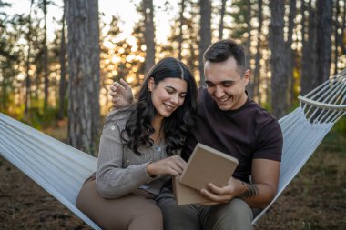 İki yetişkin yetişkin beyaz erkek ve kadın çift erkek ve kız arkadaş ya da karı koca hediye kutusu hediye ederken orman parkında oturup romantik aşkı kutluyorlar gerçek insanlar uzay kopyaları yapıyorlar.
