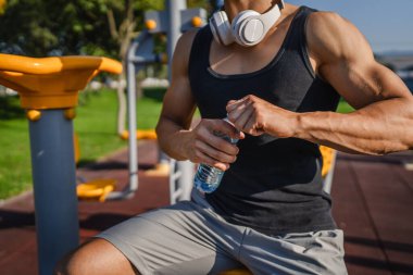 Beyaz tenli bir erkek sporcu plastik su şişesini açık tutuyor ve açık havada güneşli su ve sağlıklı yaşam tarzı konsepti fotokopi çekerken içmeye hazırlanıyor.