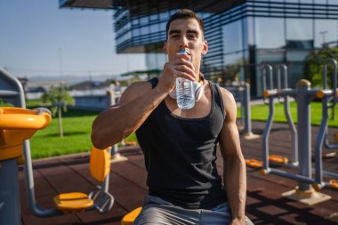 Beyaz tenli bir erkek sporcu plastik su şişesini açık tutuyor ve açık havada güneşli su ve sağlıklı yaşam tarzı konsepti fotokopi çekerken içmeye hazırlanıyor.