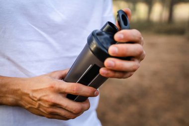 Kafkas kökenli genç bir erkek sporcu açık havada, ormandaki parkta ya da doğadaki ormanlık alanda çalışırken fren yapıyor. Elinde güçlü ve mutlu bir kopya alanı tutuyor.