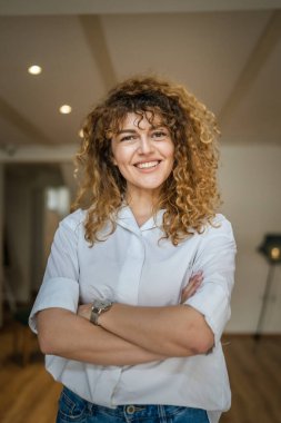 Kafkasyalı bir kadın kendine güveni tam, kafenin içinde kıvırcık saç portresiyle duruyor, gülümsüyor, gerçek bir insan mekanı kopyalıyor.