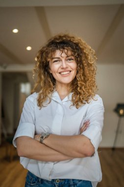 Kafkasyalı bir kadın kendine güveni tam, kafenin içinde kıvırcık saç portresiyle duruyor, gülümsüyor, gerçek bir insan mekanı kopyalıyor.