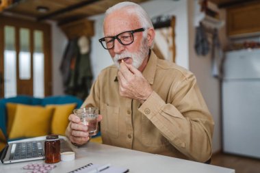 Kafkasyalı bir erkek büyükbaba evde oturur uyuşturucu tableti alır ağrı kesici içer ya da vitamin takviyesi alır. Etikette tıbbın gerçek insan sağlığı ve tıp kavramını okur.