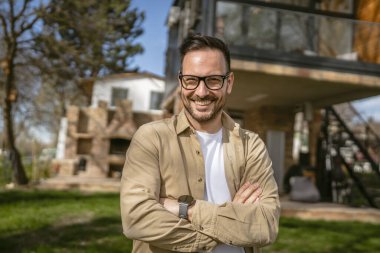 Bir modern yetişkin beyaz erkek portresi sakallı ve gözlüklü erkek evinin önünde duruyor. Mutlu, kendinden emin fotokopi odası.