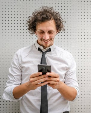 Kafkasyalı bir erkek işadamı telefon etmek ya da mesaj göndermek için akıllı cep telefonu kullanıyor. Açık havada mesaj atıyor. Açık havada beyaz gömlek giyiyor.