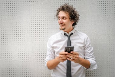 Kafkasyalı bir erkek işadamı telefon etmek ya da mesaj göndermek için akıllı cep telefonu kullanıyor. Açık havada mesaj atıyor. Açık havada beyaz gömlek giyiyor.