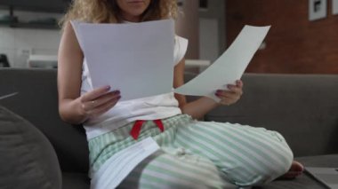 Beyaz bir kadın evde ders çalışıyor. Sınav kağıtlarını okuyup hazırlıyor. Gerçek insanlar kanepede otururken ellerinde kağıt belgeler ya da mektuplar tutuyor. 