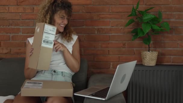 ある女性の慎重な大人の女性は オンラインビデオ通話の遅い動きを持つ自宅のラップトップコンピュータの前に開いた読書カード幸せな笑顔のプレゼントを受け取ります — ストック動画