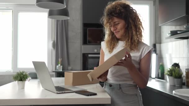 ある女性の慎重な大人の女性は オンラインビデオ通話の遅い動きを持つ自宅のラップトップコンピュータの前に開いた読書カード幸せな笑顔のプレゼントを受け取ります — ストック動画