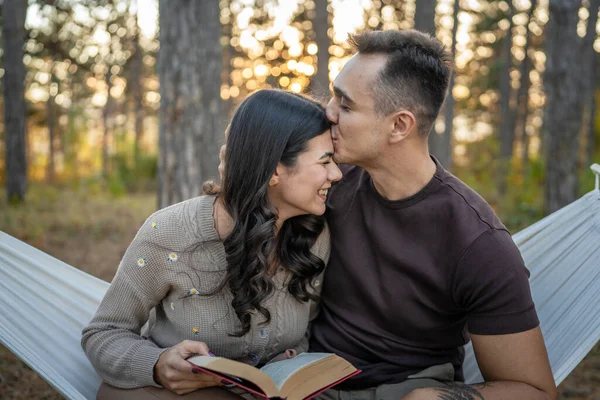Man and woman young adult couple in nature hold and read book in love