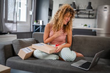 Kafkasyalı yetişkin bir kadın, evinde online video görüşmesi yapan dizüstü bilgisayarın önünde açık kart okuyup mutlu bir gülümseme alıyor.