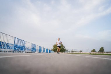 Koşu parkurunda koşan beyaz bir adam. Stadyum erkek sporcusu. Güneşli bahar ve yaz günlerinde koşuyor.