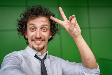 Kafkasyalı yetişkin bir adamın portresi açık havada durur beyaz gömlek giyer ve kravat takar mutlu bir gülümseme takınır fotokopi alanı duvarın önünde durur kendine güvenen bir işadamı modern binanın önünde poz verir.