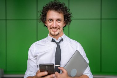 Kafkasyalı bir erkek işadamı telefon etmek ya da mesaj göndermek için akıllı cep telefonu kullanıyor. Açık havada mesaj atıyor. Açık havada beyaz gömlek giyiyor.