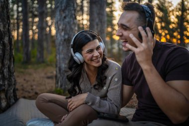 Erkek ve kadın, genç yetişkin bir çift kulaklıkla müzik dinliyor.