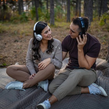 Erkek ve kadın, genç yetişkin bir çift kulaklıkla müzik dinliyor.