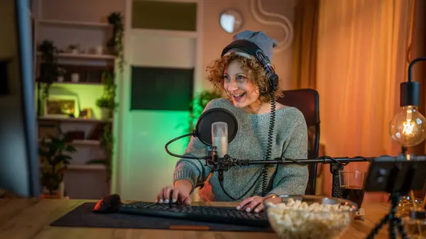 Mature woman play video games on pc computer while streaming to social media or internet online playtrough or walktrough video female gamer having fun at home wear headphone happy winning copy space