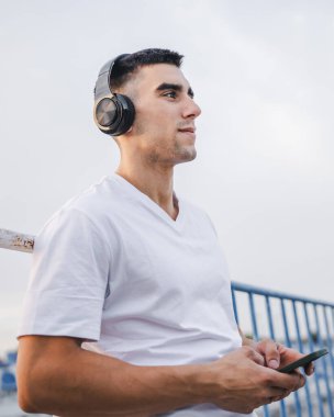 Sabah koşarken cep telefonu kullanan bir sporcunun portresi kulaklıkla müzik dinleyen atletik bir adam cep telefonu uygulaması kullanıyor