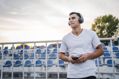 Sabah koşarken cep telefonu kullanan bir sporcunun portresi kulaklıkla müzik dinleyen atletik bir adam cep telefonu uygulaması kullanıyor