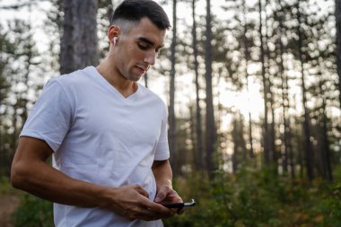 Sabah koşarken cep telefonu kullanan bir sporcunun portresi kulaklıkla müzik dinleyen atletik bir adam cep telefonu uygulaması kullanıyor