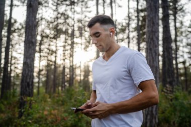 Sabah koşarken cep telefonu kullanan bir sporcunun portresi kulaklıkla müzik dinleyen atletik bir adam cep telefonu uygulaması kullanıyor