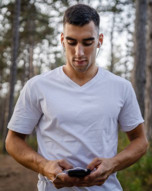 Sabah koşarken cep telefonu kullanan bir sporcunun portresi kulaklıkla müzik dinleyen atletik bir adam cep telefonu uygulaması kullanıyor