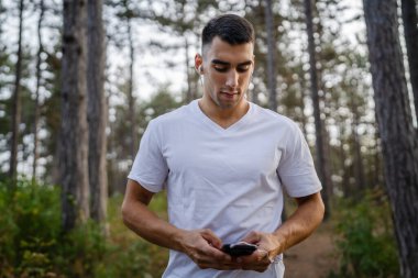 Sabah koşarken cep telefonu kullanan bir sporcunun portresi kulaklıkla müzik dinleyen atletik bir adam cep telefonu uygulaması kullanıyor