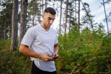 Sabah koşarken cep telefonu kullanan bir sporcunun portresi kulaklıkla müzik dinleyen atletik bir adam cep telefonu uygulaması kullanıyor