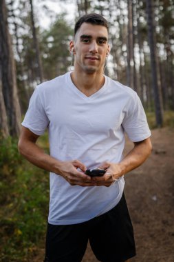 Sabah koşarken cep telefonu kullanan bir sporcunun portresi kulaklıkla müzik dinleyen atletik bir adam cep telefonu uygulaması kullanıyor