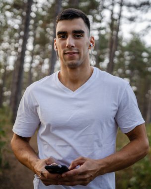 Sabah koşarken cep telefonu kullanan bir sporcunun portresi kulaklıkla müzik dinleyen atletik bir adam cep telefonu uygulaması kullanıyor