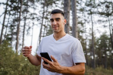 Sabah koşarken cep telefonu kullanan bir sporcunun portresi kulaklıkla müzik dinleyen atletik bir adam cep telefonu uygulaması kullanıyor