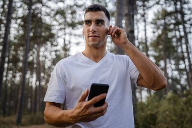 Sabah koşarken cep telefonu kullanan bir sporcunun portresi kulaklıkla müzik dinleyen atletik bir adam cep telefonu uygulaması kullanıyor